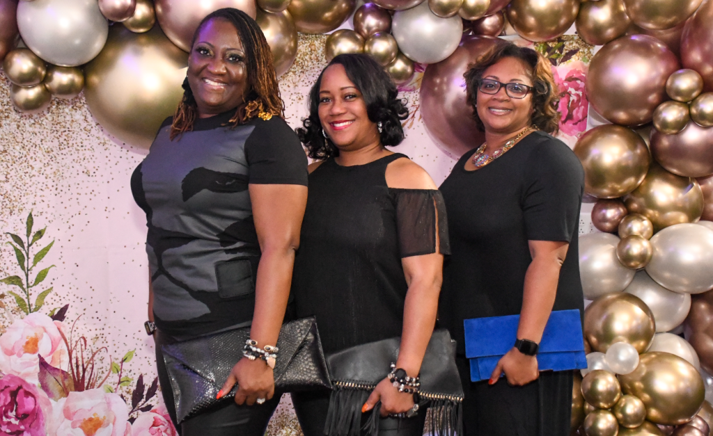 African-American women posing in front of a balloon background