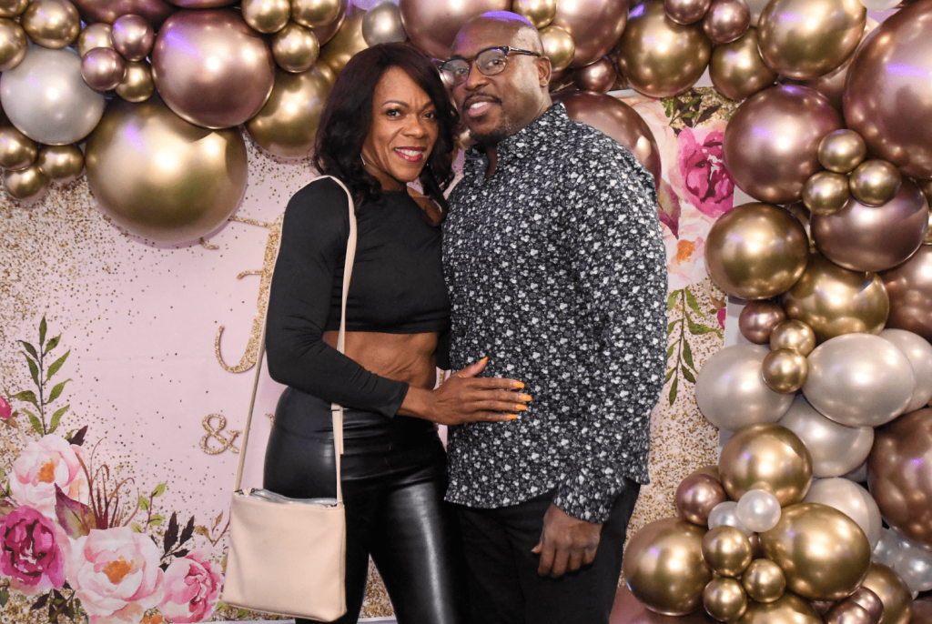 African-American couple posing in front of a balloon background