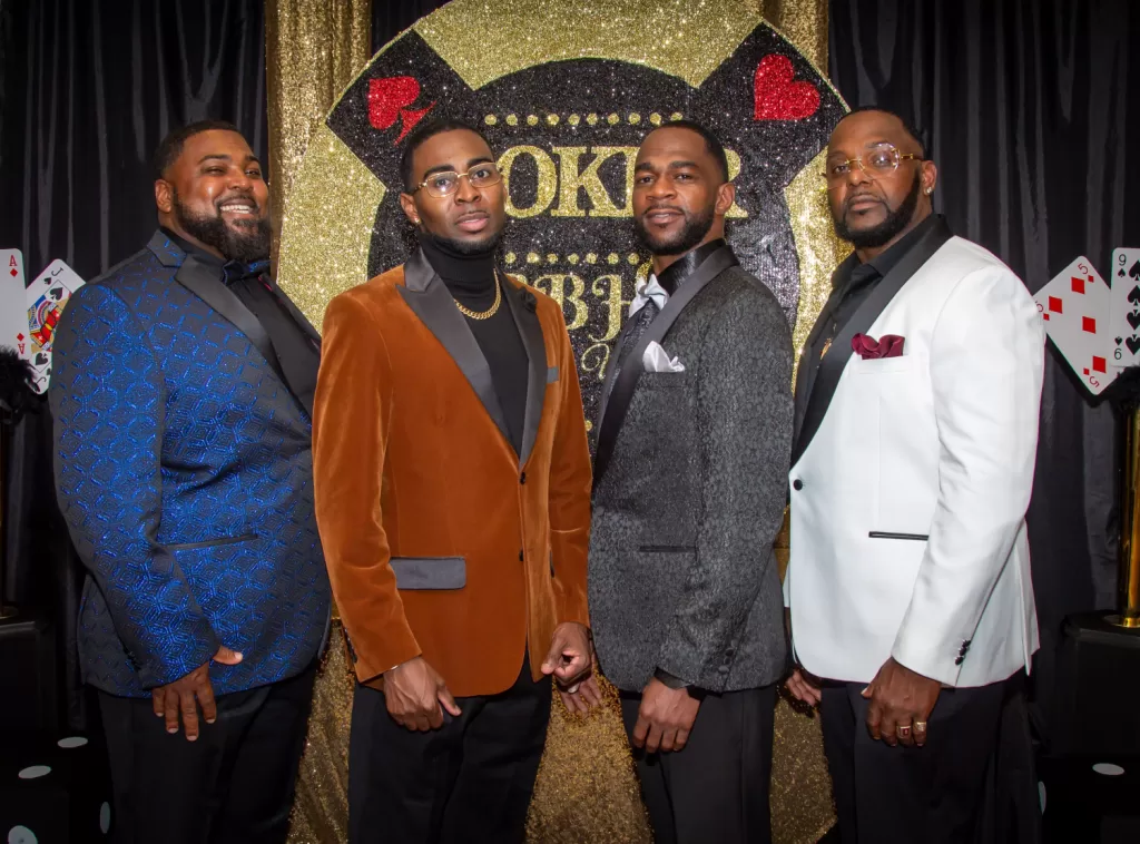 African-American men posing in front of black and gold poker background